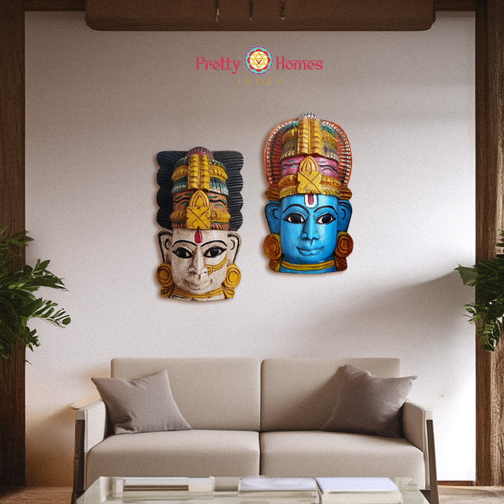 Pair of hand painted wooden deity masks in blue and white displayed above sofa living room