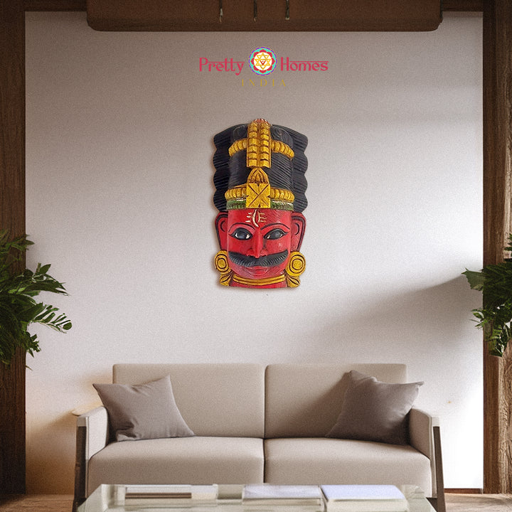 Staged living-room photo of a carved wooden red face mask with tall ornamental headdress.