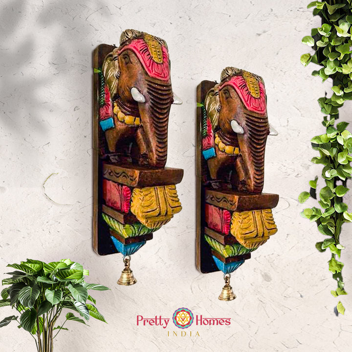 Set of two hand-painted wooden elephant wall brackets with bright accents and dangling bells.