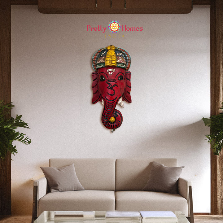 Red hand-painted wooden Ganesha face mask with decorative crown and hanging hook.