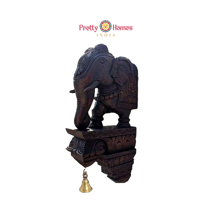 Hand-carved dark-wood elephant corbel shelf with decorative brass bell and carved detailing.
