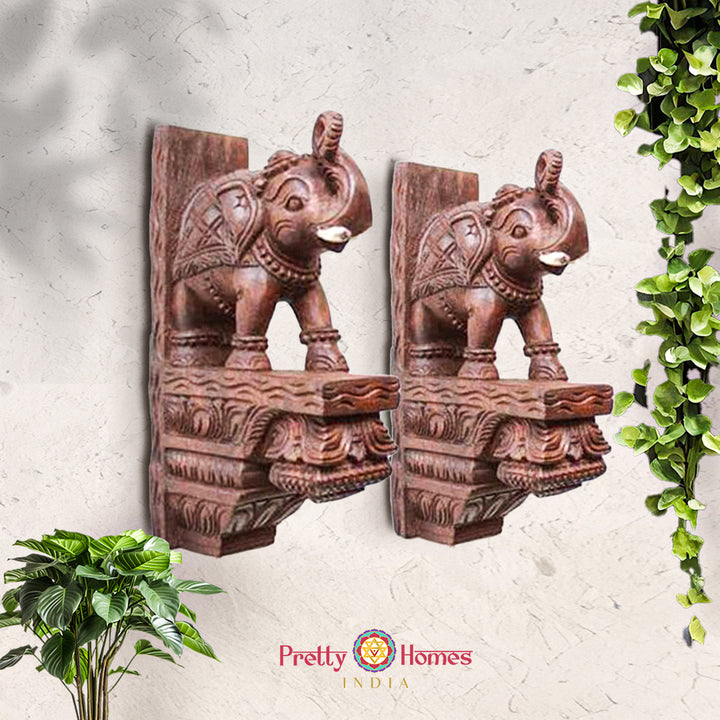 Pair of carved wooden elephant corbel shelves in natural wood finish, shown as matching set.