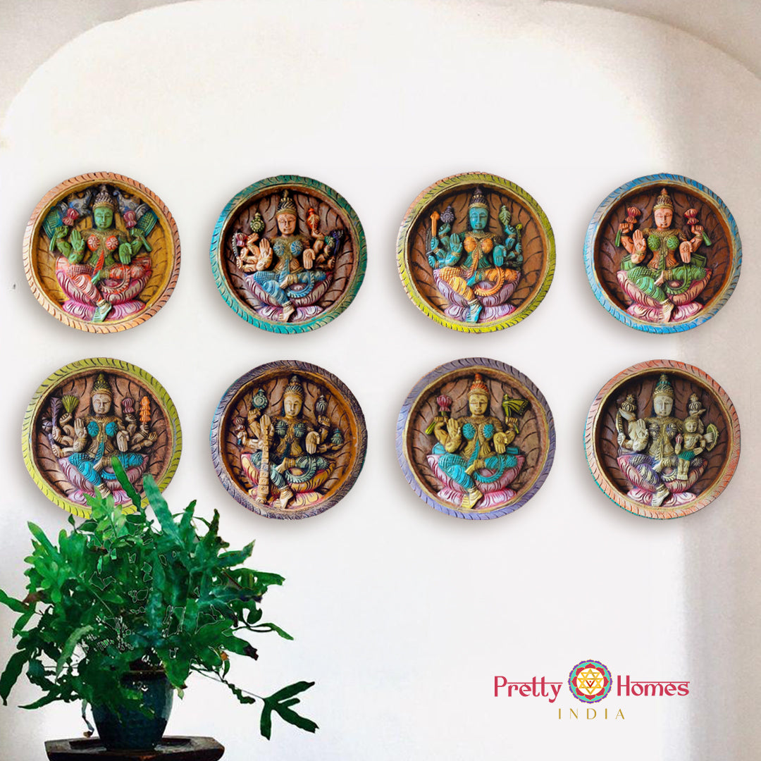 A set of eight round carved wooden panels with Hindu deity figures, displayed on a wall with a green plant beside them.