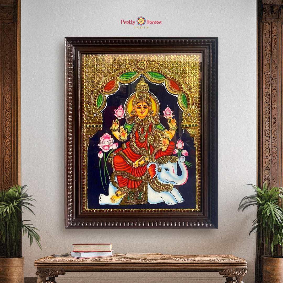 Framed Gajalakshmi Tanjore painting in gold foil displayed in traditional setting