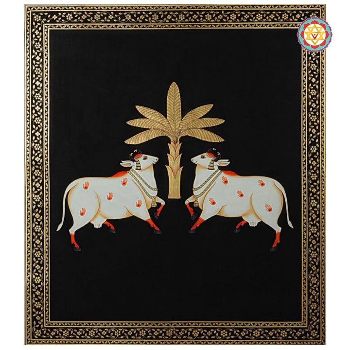 Close-up of pichwai painting with pair of sacred cows and gold tree on deep black canvas.
