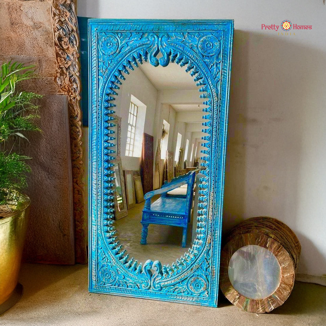 Blue wood carved floor mirror placed by wall