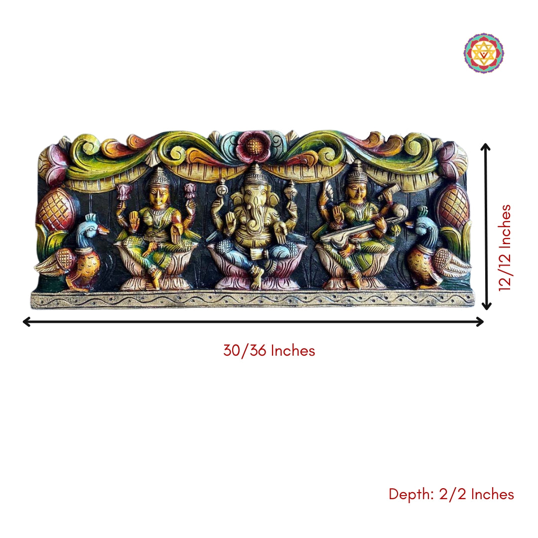 Hand-carved wooden wall panel featuring Hindu deities Ganesh, Lakshmi, and Saraswati with peacocks on the sides, measured depth and height.