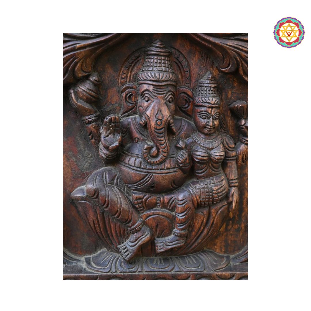 Wooden carving of a deity with intricate details on a white background. Panel showing full divine figure of seated Ganesha

