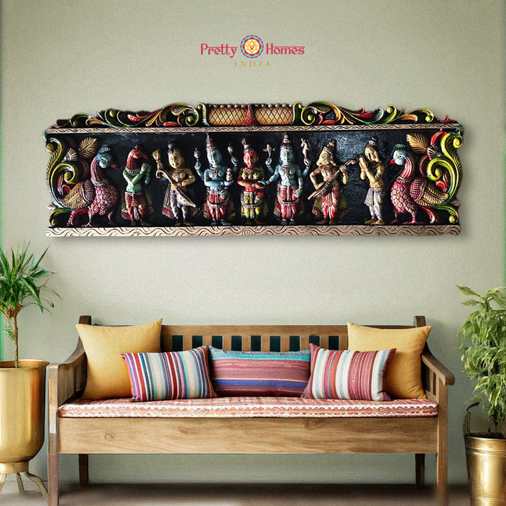 Decorative wall art with colorful figures above a wooden bench with striped cushions - Horizontal wooden wall panels with Shiva-Parvati wedding in gopuram style

