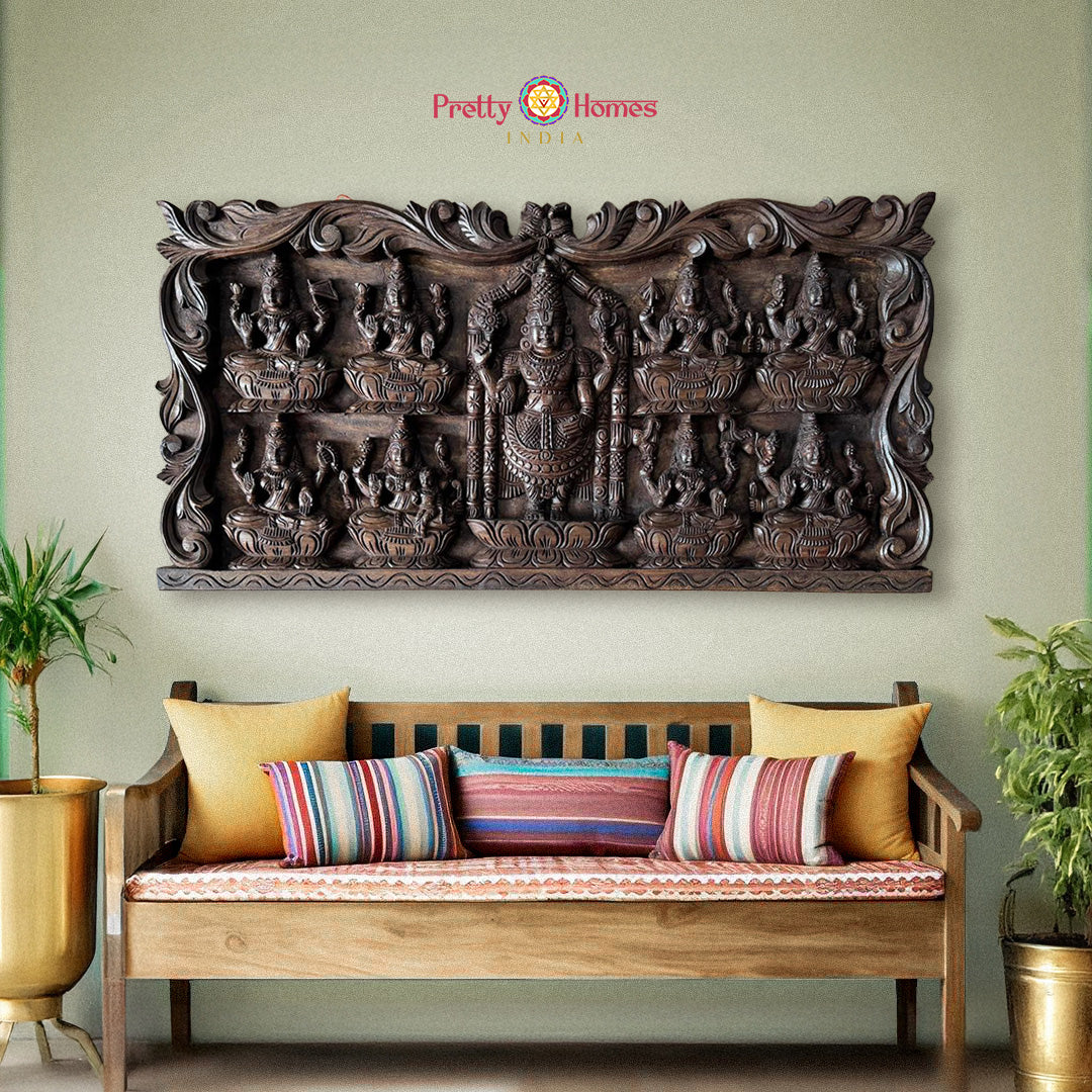 Decorative wooden wall panel above a wooden bench with colorful cushions on a light green wall: Carved wooden panels with Tirupati Balaji and Ashtalakshmi carvings

