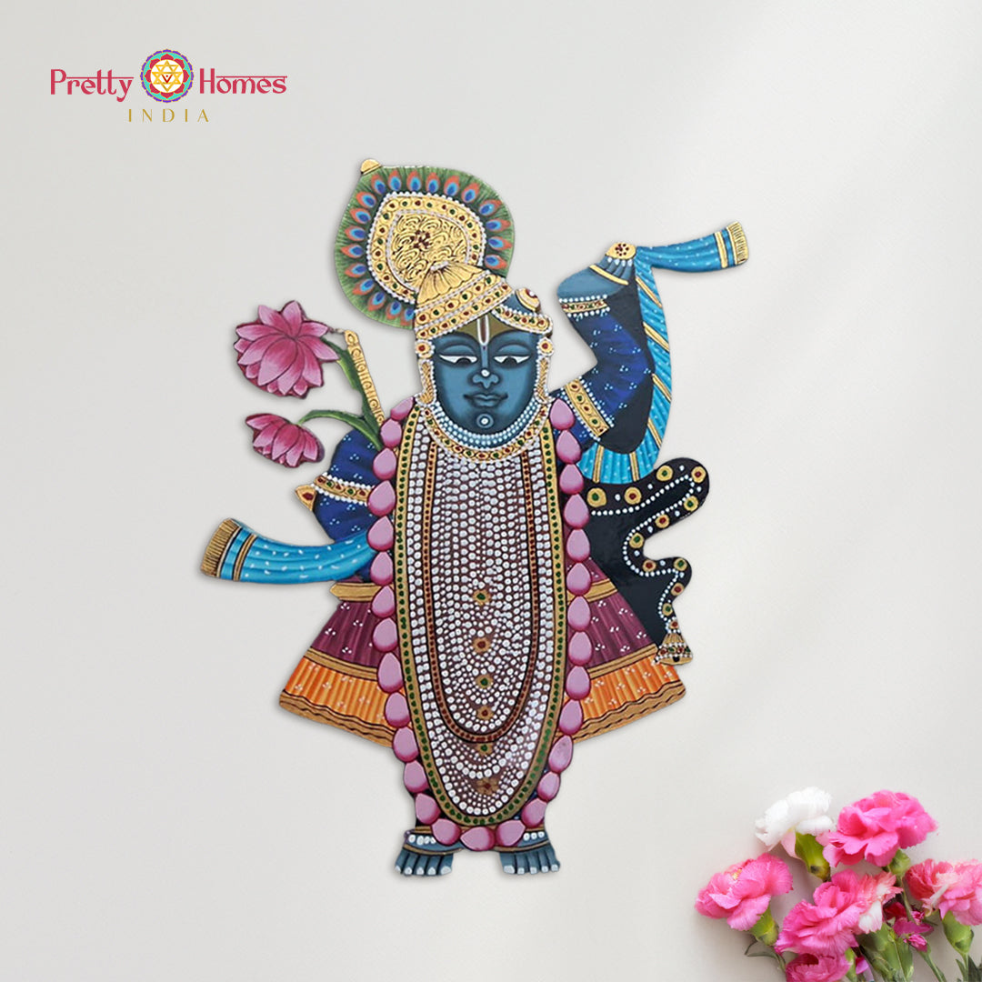 Hand-painted Shrinathji cutout in Pichwai style placed near pink flowers.