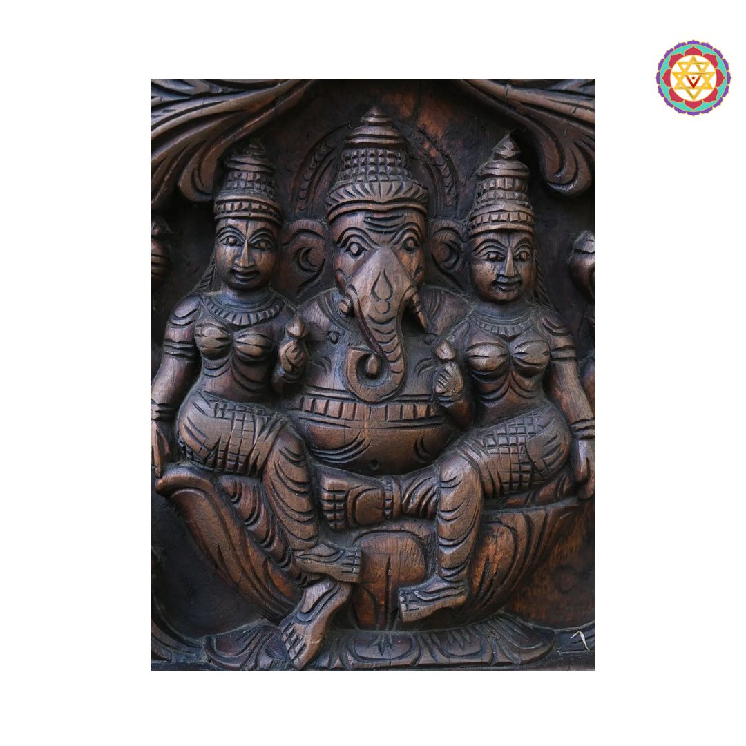 Wooden carvings of three figures with a central elephant-headed figure on a white background. Zoomed view of Ganesha’s sacred symbols and posture

