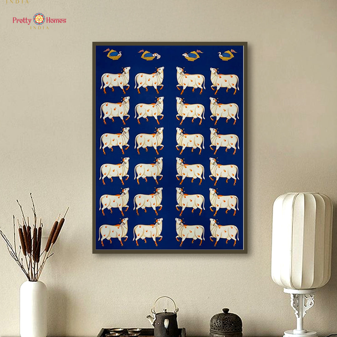 Contemporary hand-painted pichwai of white cows on a blue background, displayed in a modern room.