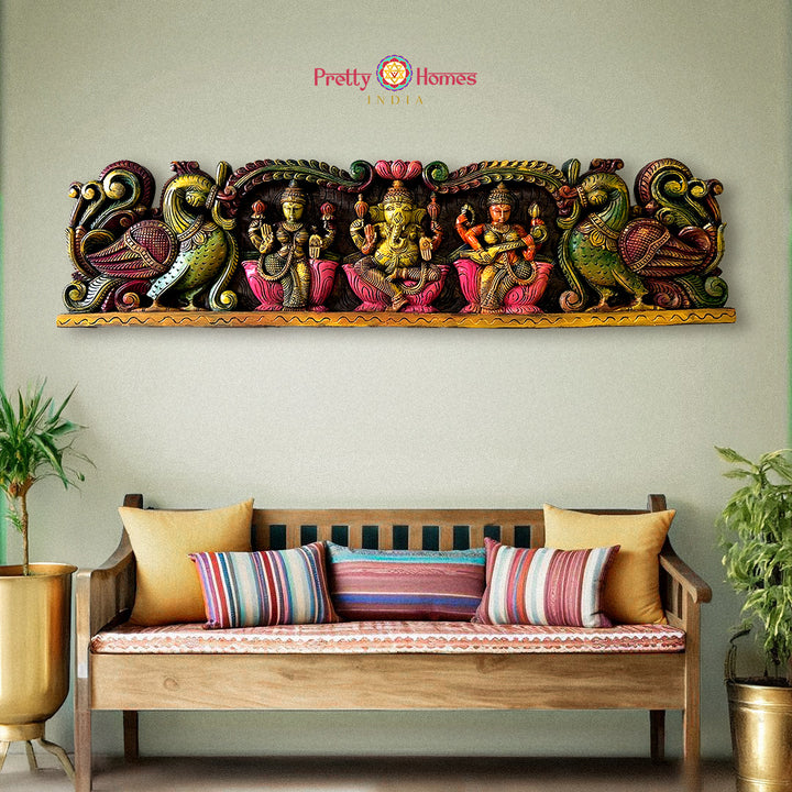 Decorative wall art with colorful figures above a wooden bench with striped cushions: Horizontal wooden wall panels with Ganesh, Laxmi & Saraswati in multicolour

