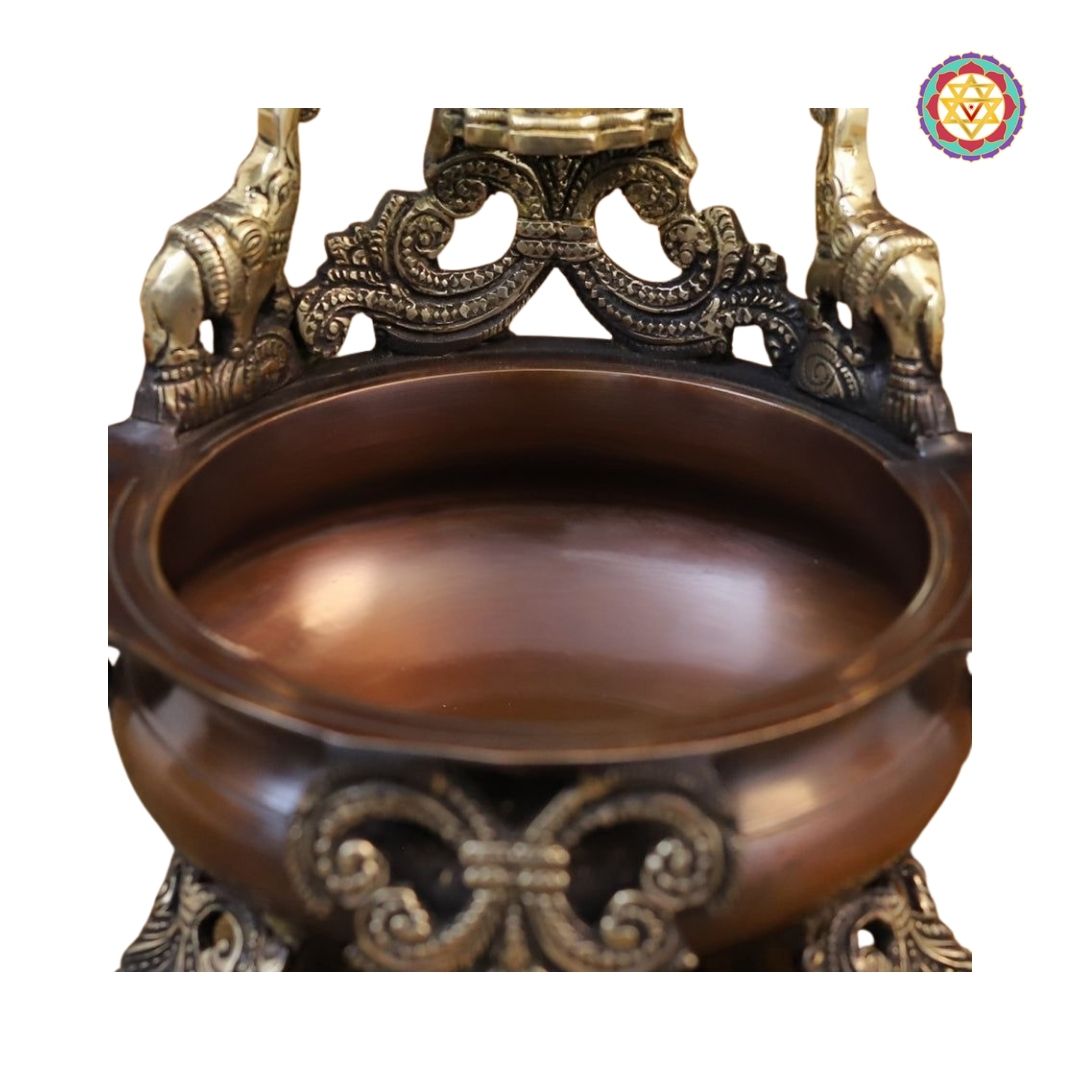 angled shot of copper urli showcasing decorative rim and Ganesh carving