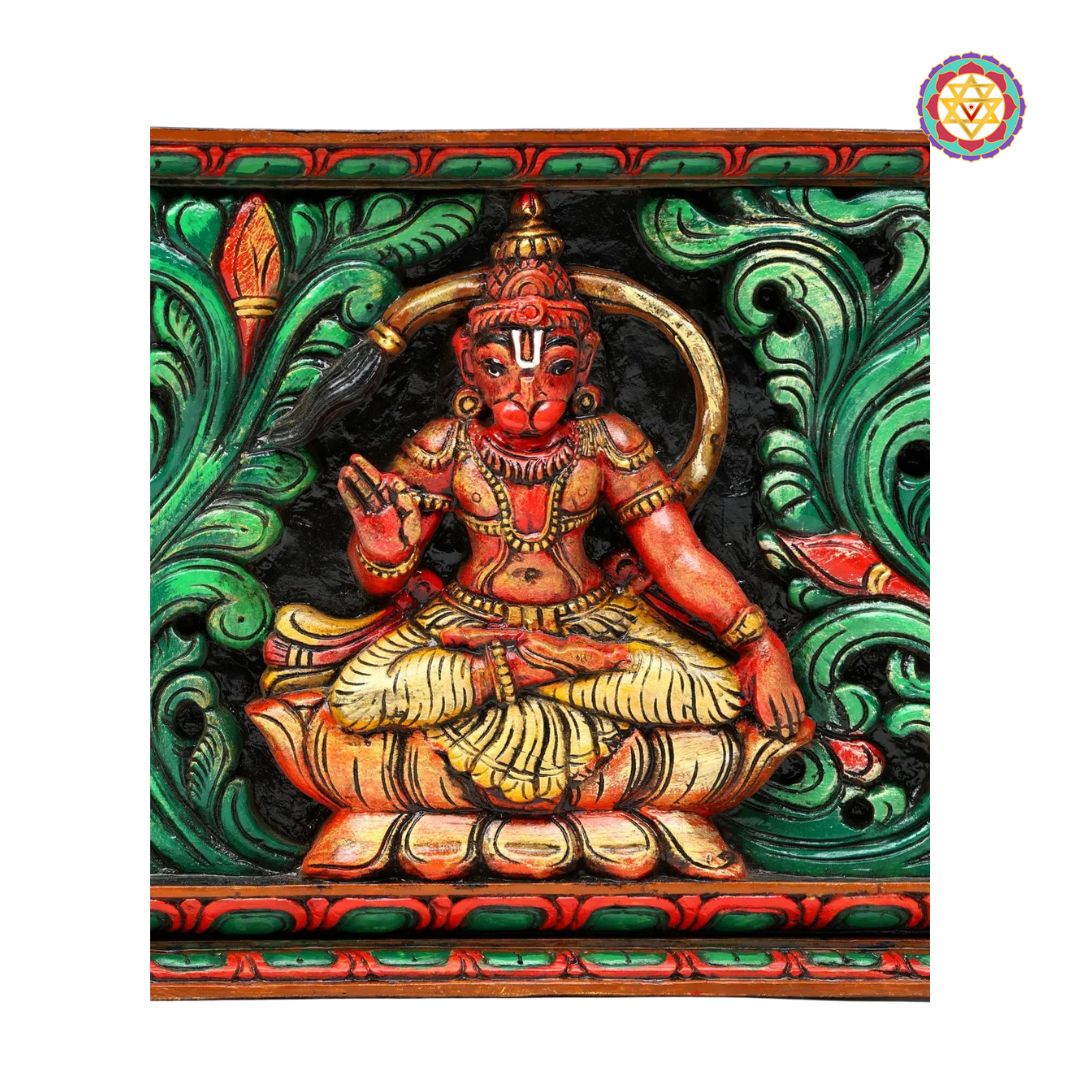 Colorful sculpture of a seated figure with intricate designs on a green background - Seated Hanuman surrounded by floral carvings