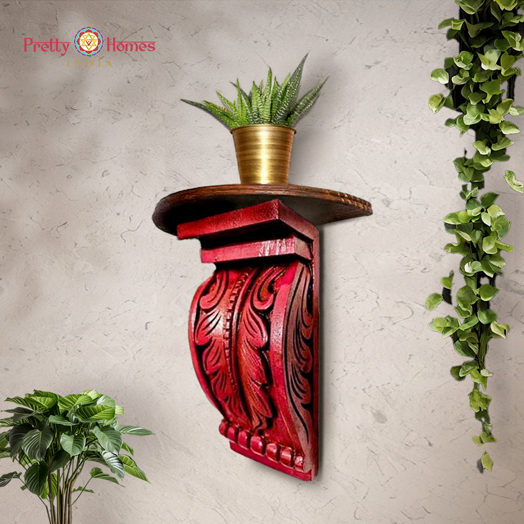 Red hand-painted carved wooden corbel shelf with carved leaf motifs and round top.
