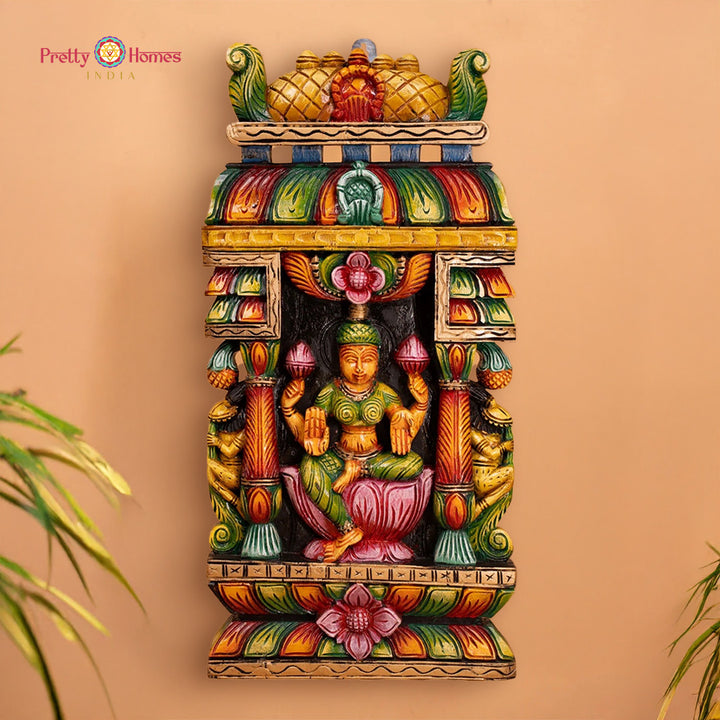 Colorful wall art with a deity figure on a beige background: Carved wooden wall panel of Goddess Laxmi with vibrant multicolour finish