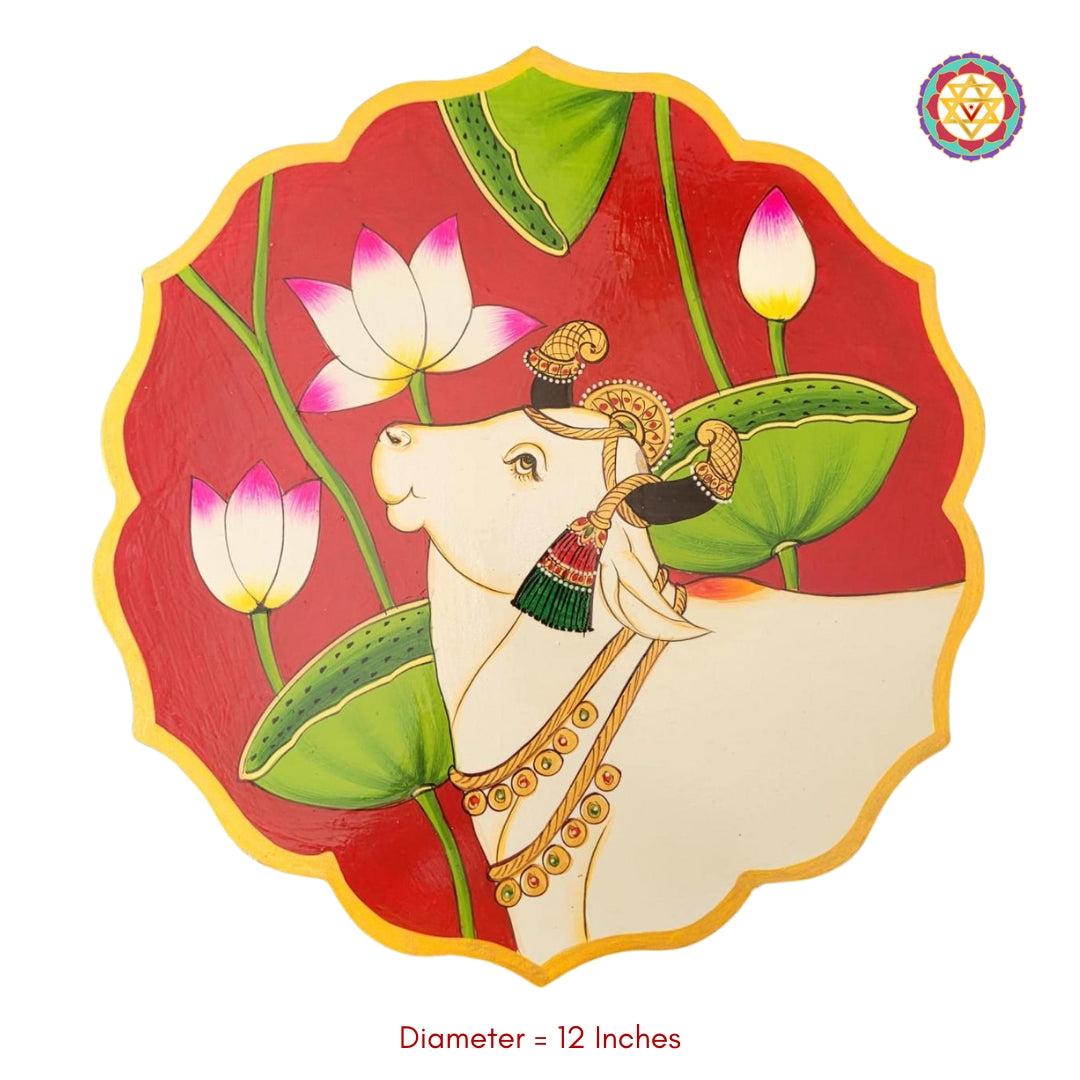 Flatlay of red petal-shaped wooden plate with pichwai painting of cow and lotus. A handcrafted pichwai home decor piece.
