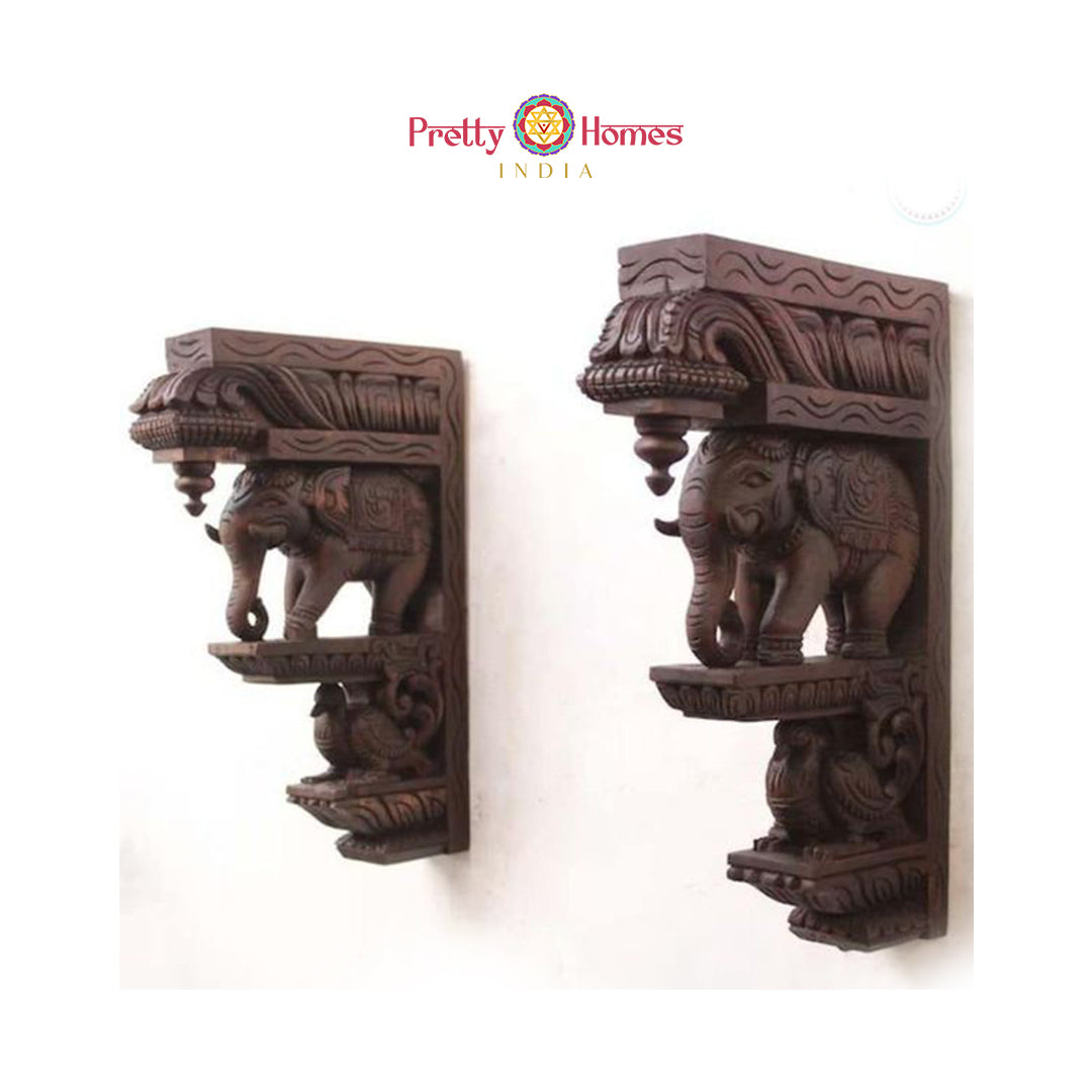 Pair of intricately carved wooden elephant corbels with ornamental overhangs and traditional motifs.