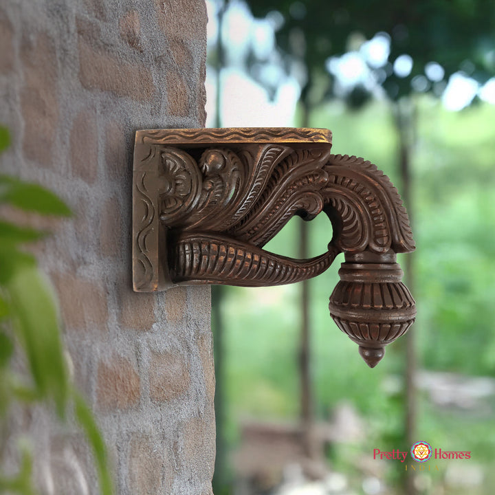 Decorative metal bracket on a stone wall with a blurred natural background