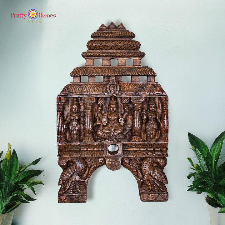 Carved wooden wall art with intricate designs on a light blue background. Kavadi panel with Lord Murugan, Valli & Deivanai in Chettinad carving

