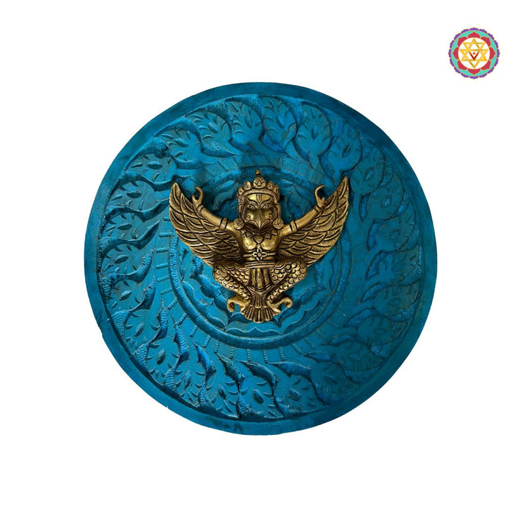Full view of round wooden frame with Garuda motif against neutral wall