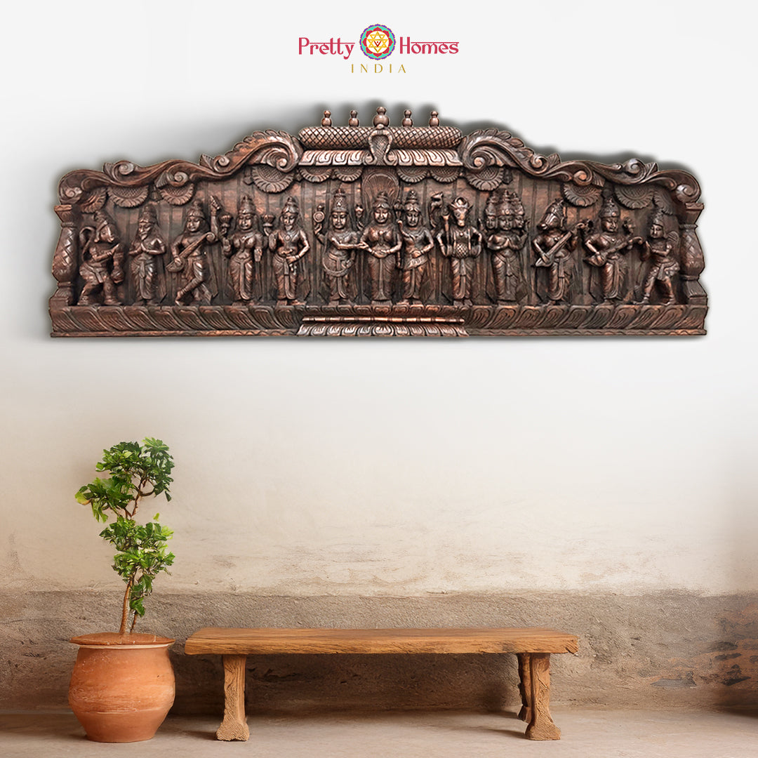 A woodcarved horizontal panel depicting a wedding scene with multiple characters, carved in brown wood with a decorative border.