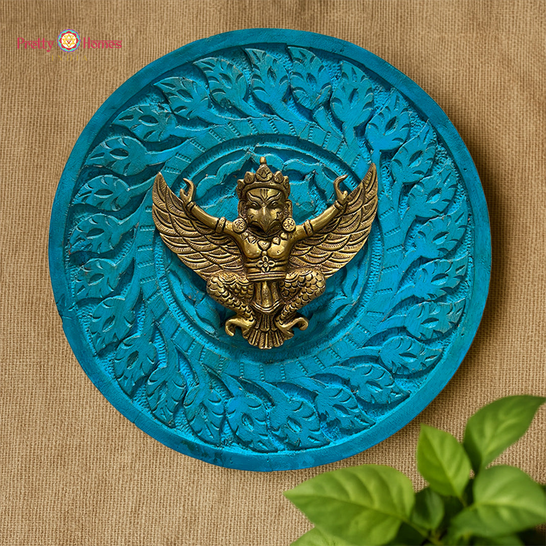 Close-up of brass Garuda figure mounted in carved round wooden frame