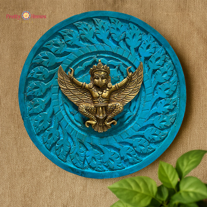 Close-up of brass Garuda figure mounted in carved round wooden frame