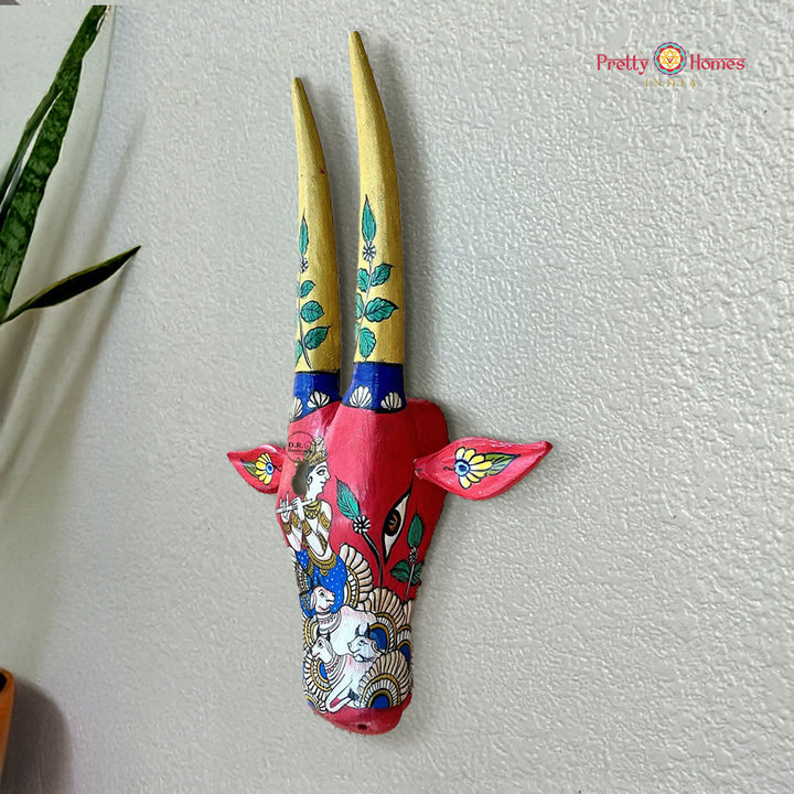 hand-painted Krishna-themed cow head wall mount in red tones with detailed face painting