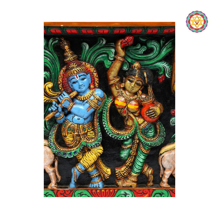 Decorative panel with two deities in colorful attire on a black background - Close-up of Venugopal Krishna carving holding flute