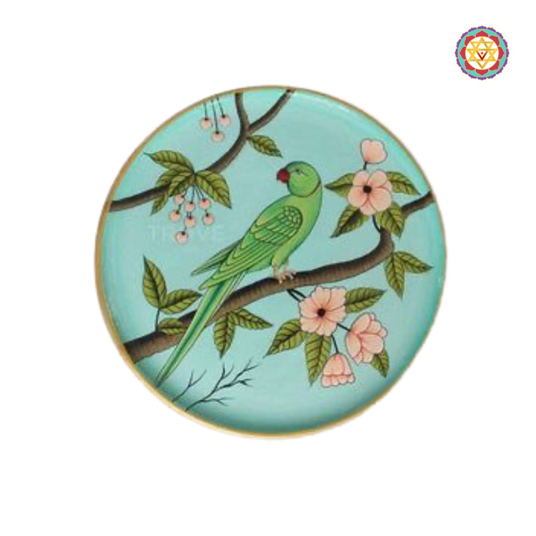 Round wall plate featuring two handpainted parrots on a soft green background.