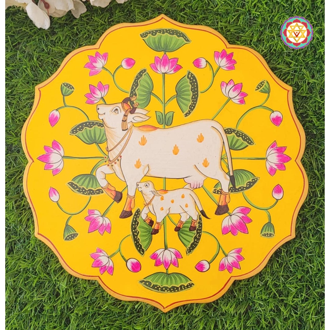 Top view of yellow 12-inch pichwai wall plate with hand-painted cow and calf. A vibrant lotus pichwai painting.