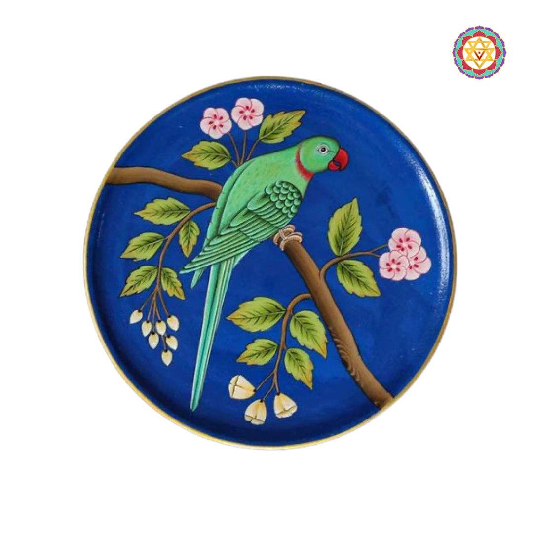 Close-up of parrot wall plate with pink flowers and dark blue base in pichwai style.