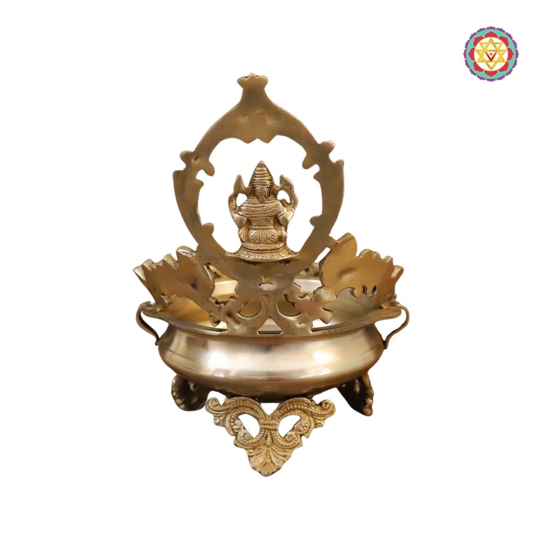 top-angle view of brass urli with Ganesh figure and engraved patterns