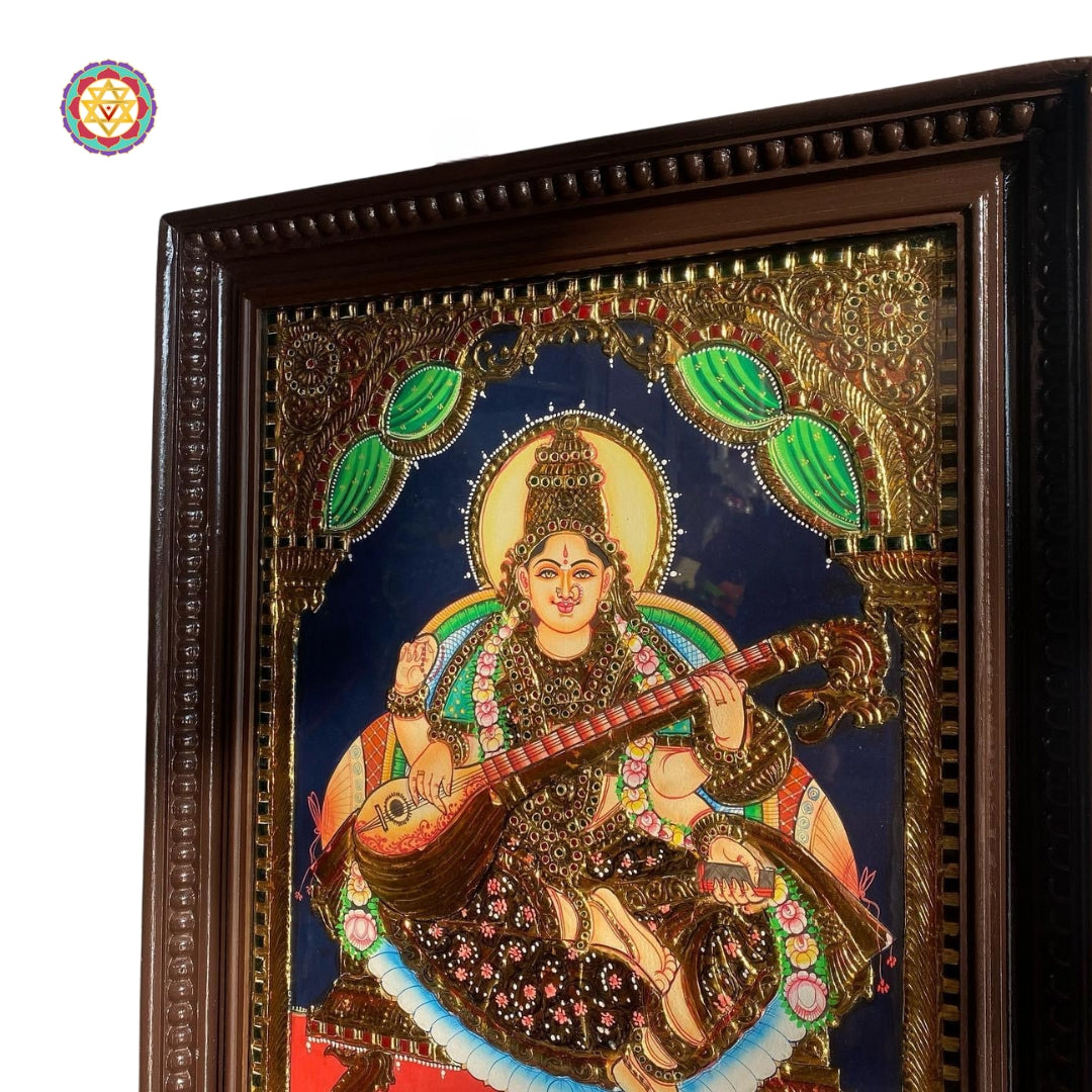 “Angled view of framed Saraswati painting showing gold foil work and teakwood detailing”