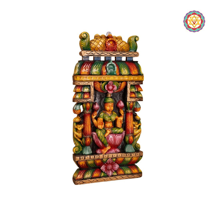 Colorful decorative statue with a figure on a white background: Side view of Laxmi gopuram-style wooden wall hanging