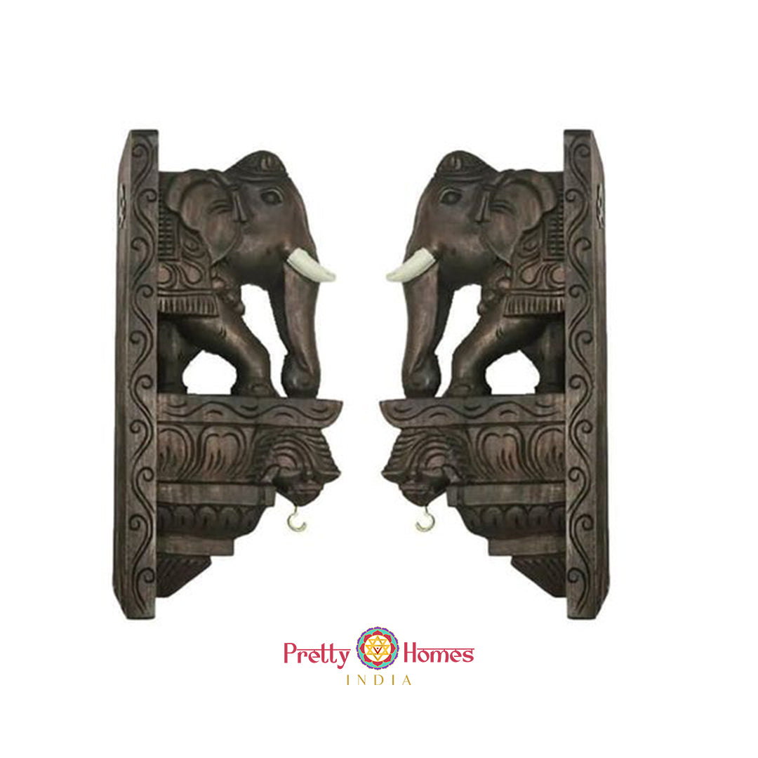 Pair of carved wooden elephant corbel brackets shown as matching wall accents.