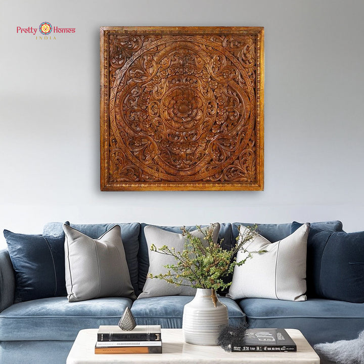 A wall-mounted, wooden panel decorative art featuring a floral pattern, displayed above a blue sofa with cushions, in a living room setting.