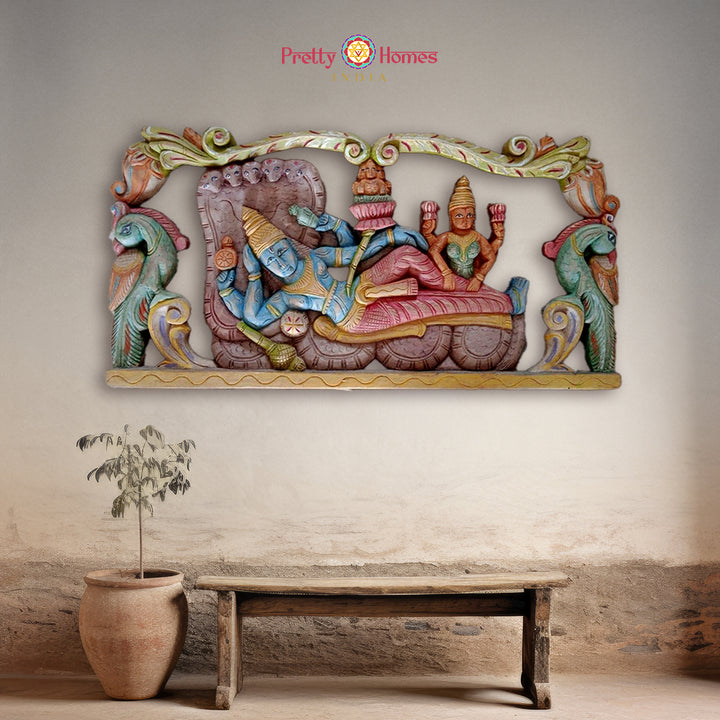 Carved wooden wall panel showing resting Vishnu with Lakshmi in antique multicolour