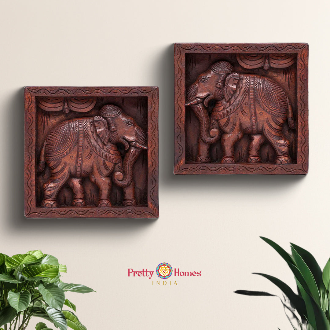 Pair of hand-carved wooden elephant wall frames on white background
