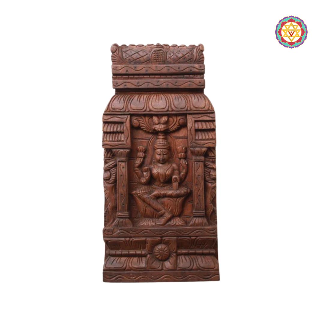 Wooden carvings on a white background: Close-up of Goddess Laxmi seated in carved temple frame

