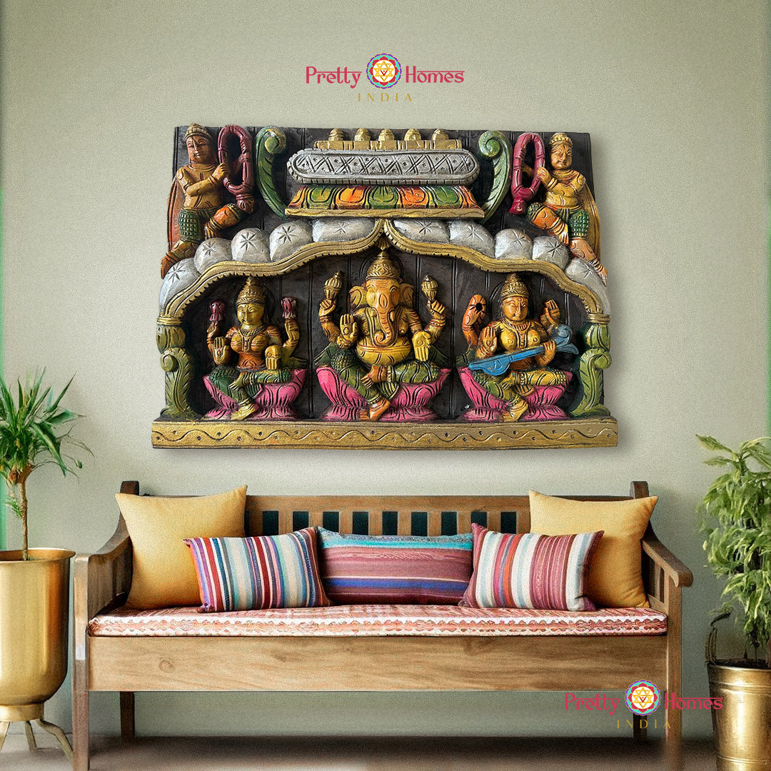 Decorative wall art with colorful figures above a wooden bench with striped cushions. Carved wooden panels with Ganesh, Laxmi, Saraswati and Gandharvas

