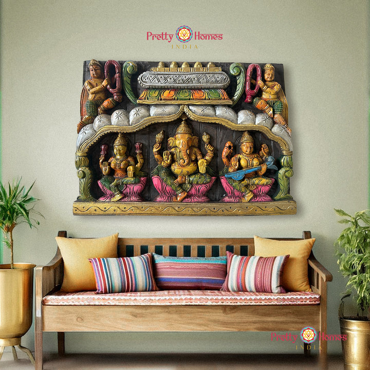 Decorative wall art with colorful figures above a wooden bench with striped cushions. Carved wooden panels with Ganesh, Laxmi, Saraswati and Gandharvas

