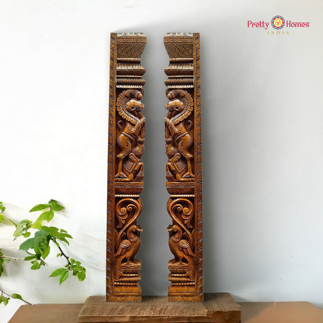 Pair of intricately carved wooden panels on a white background with 'Pretty Homes India' branding. Vertical wooden wall panel pair with Yali and peacock carvings