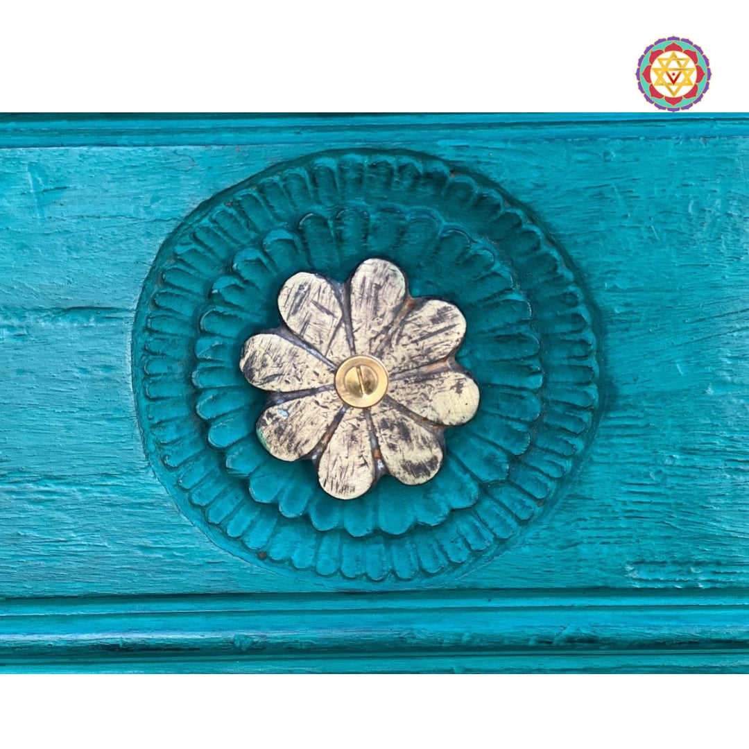 Close-up of central brass flower on rustic green wood