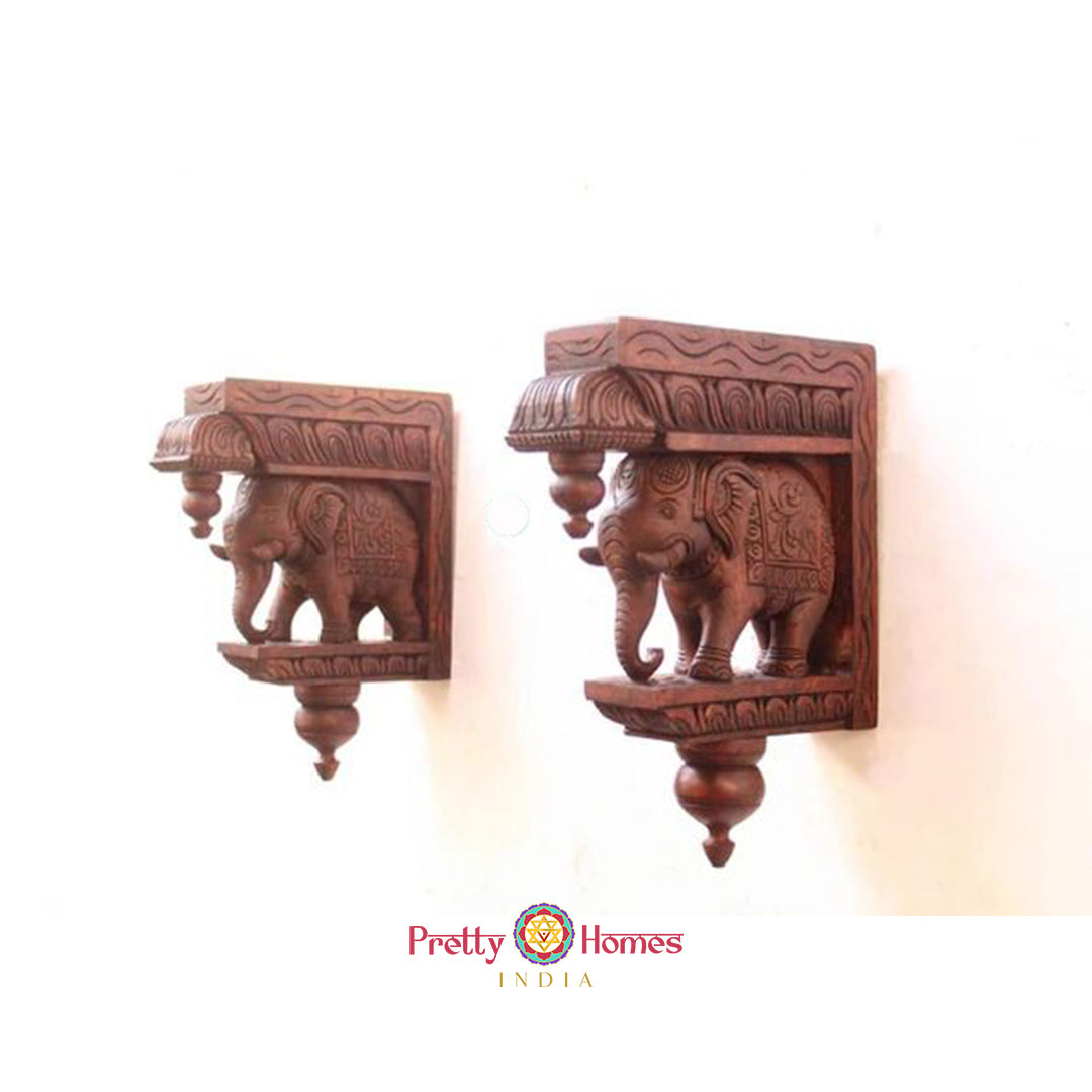 Two carved wooden elephant corbels displayed side-by-side on a white background.