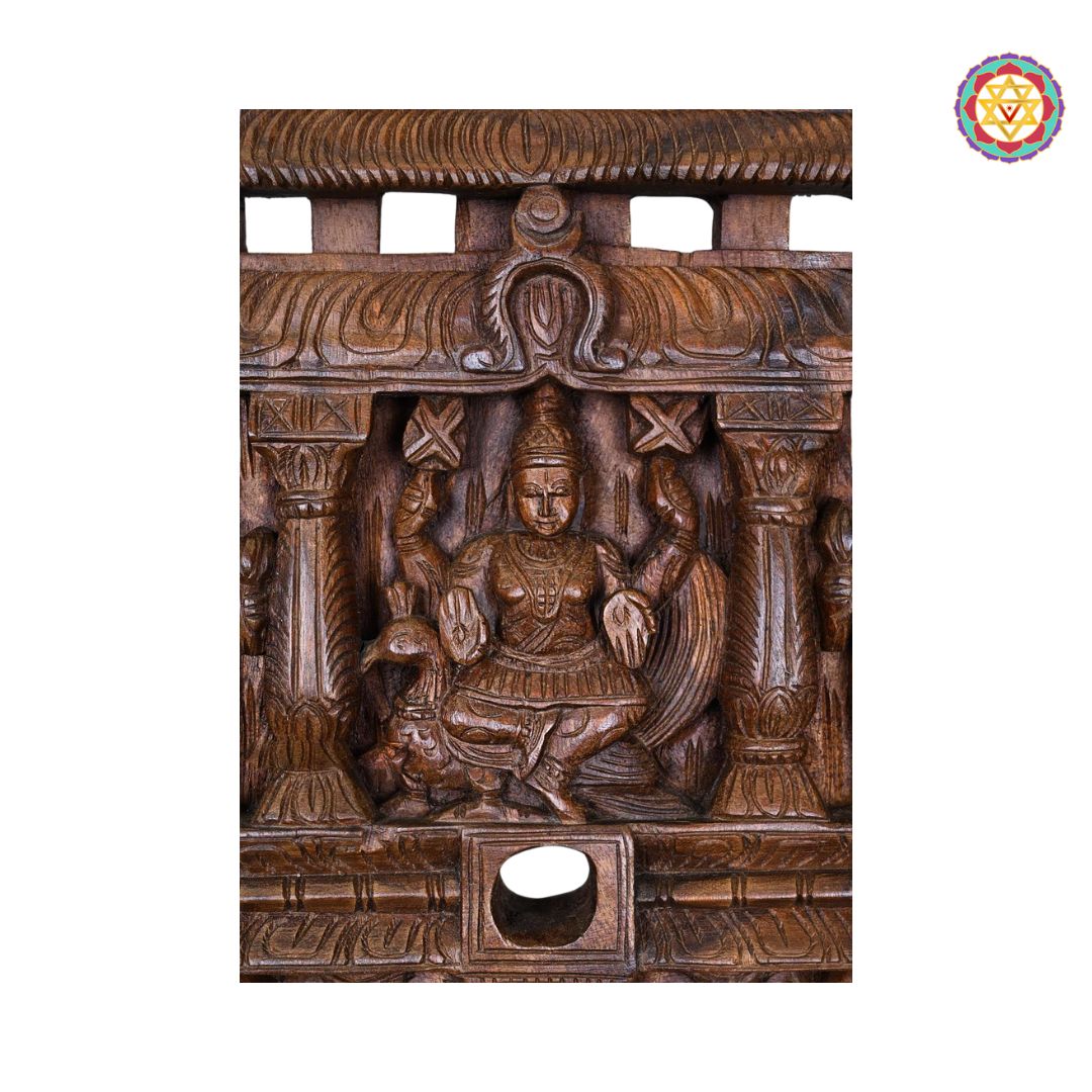 Wooden carvings of a seated figure with intricate details on a white background. Front view of Chettinad-style Murugan wall hanging panel

