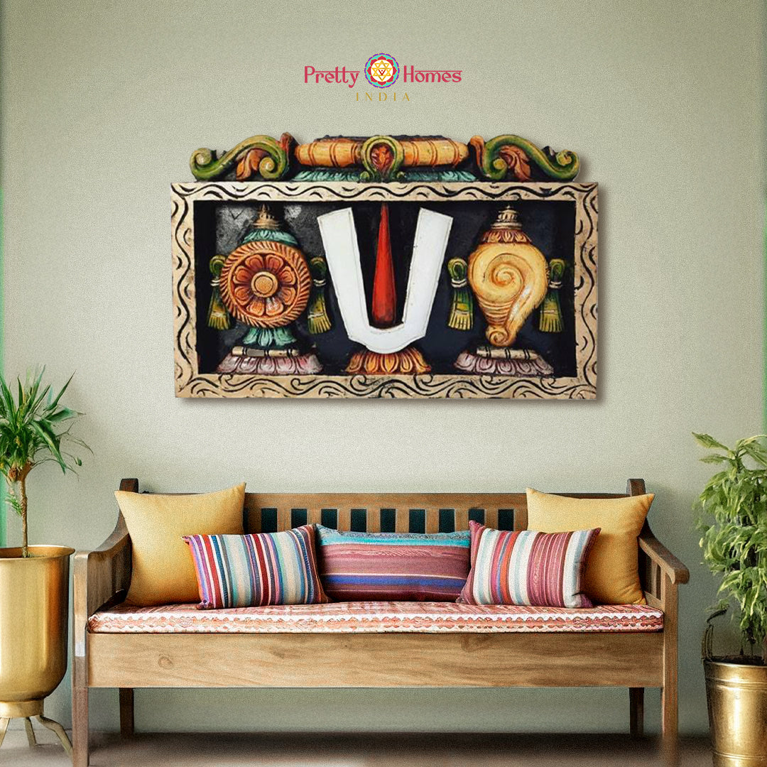 Framed wooden Balaji panel with Thiruman, Shankhu, and Chakram symbols on a wall
